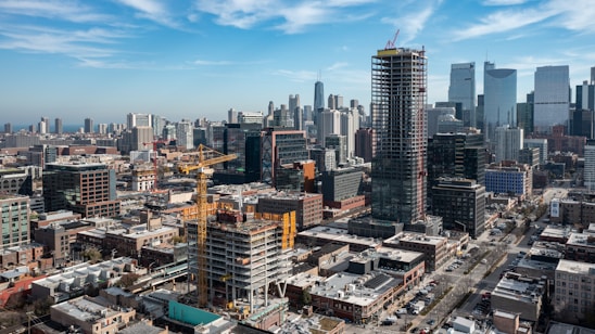 A confident consultant reviewing blueprints with a city skyline of large construction projects in the background.