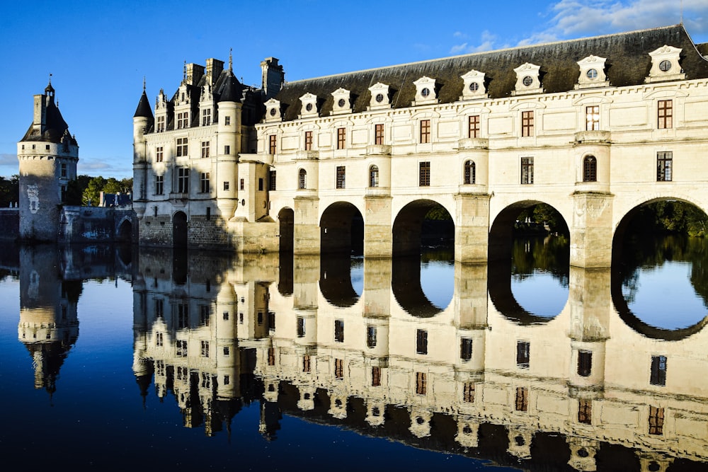 un grand bâtiment blanc aux fenêtres cintrées avec le château de Chenonceau en arrière-plan