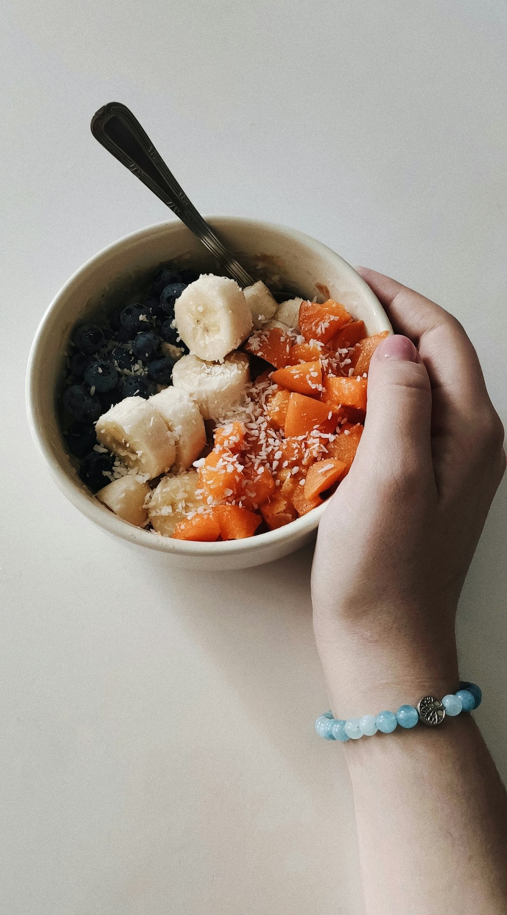 a hand holding a spoon in a bowl of food