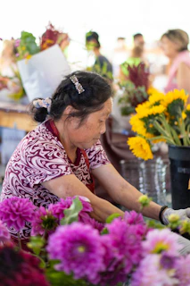 Artisan arranging fresh flowers with care in a vibrant market setting.