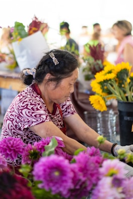 Artisan arranging a bouquet of local Tenancingo flowers in a market stall.