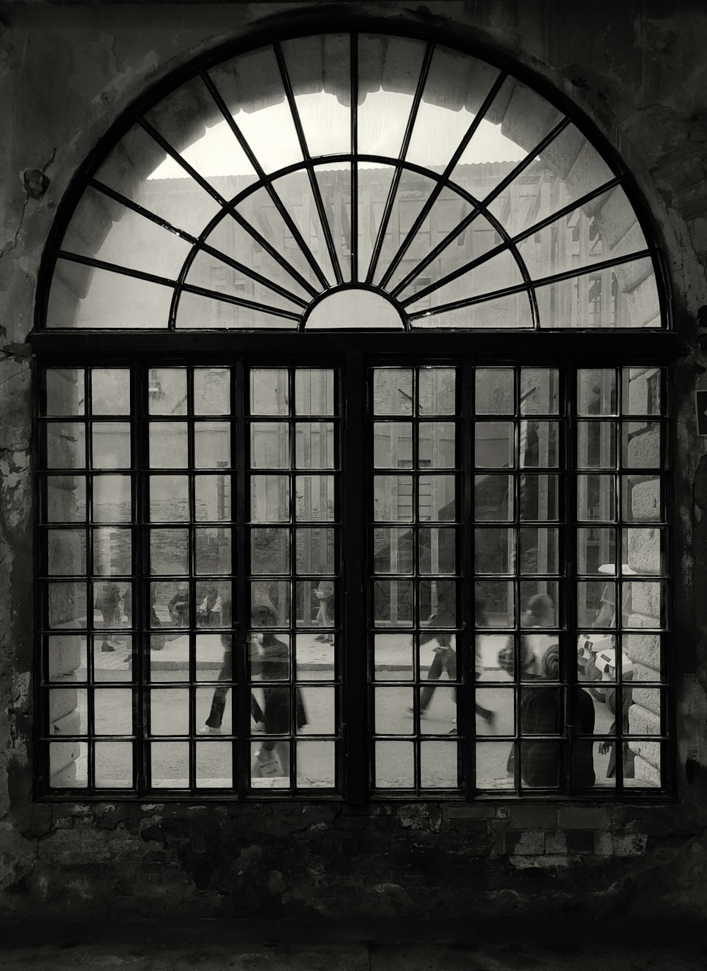 a black and white photo of a large window with a group of people inside