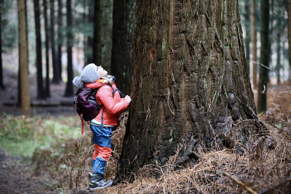 a person in a red jacket standing next to a tree