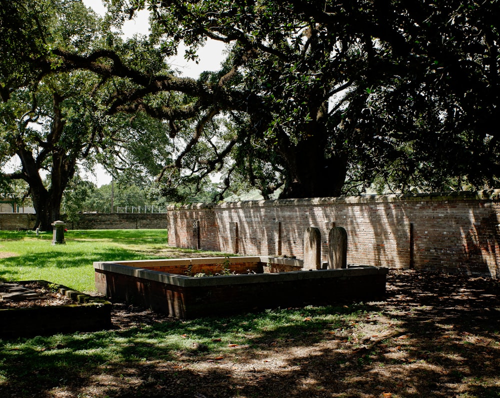 a stone wall with a bench in a park