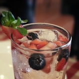 A refreshing strawberry-flavored soft drink poured into a tall glass with fresh berries on the side
