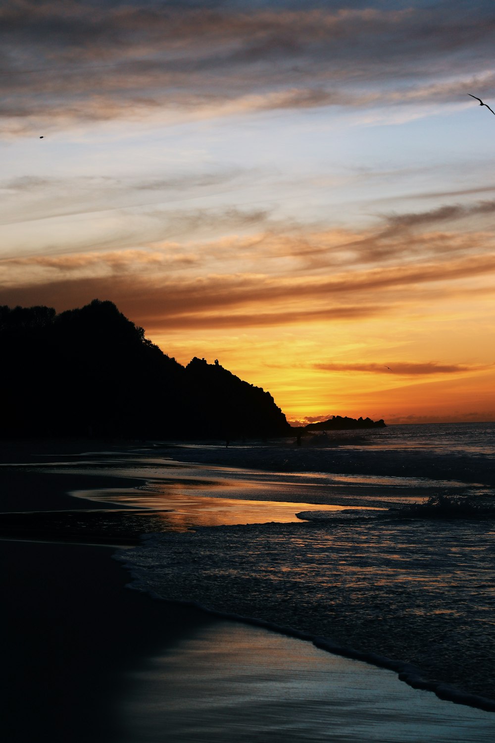 uma praia com uma colina no fundo