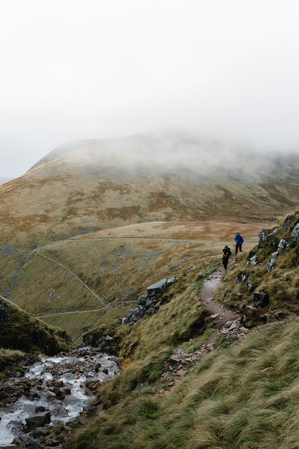 a group of people walking on a path in a hilly area