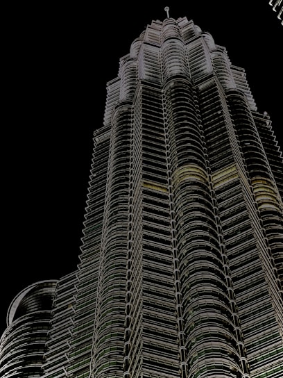 A sleek, futuristic high-rise tower illuminated at dusk, showcasing imarat's precision engineering and architectural innovation.