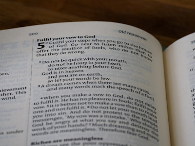 A close-up of an open book showing a page from the Old Testament. The text includes biblical verses and instructions about making vows to God. The page number 500 is seen at the top.