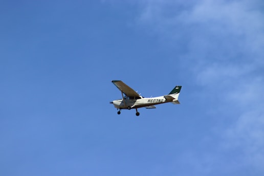 A small propeller airplane is flying against a clear blue sky. The aircraft has a distinctive tail number visible on its side.