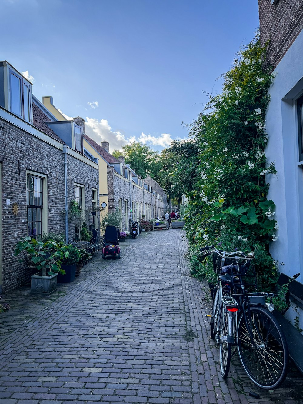 a brick road with bicycles parked on it and buildings on the side