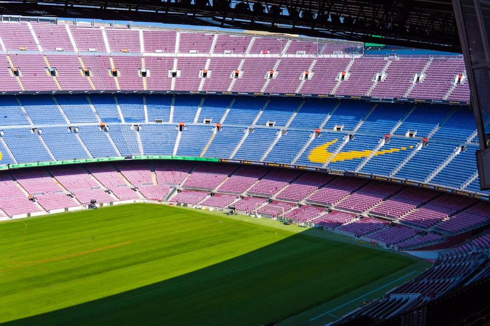 a sports stadium with a green field with Camp Nou in the background