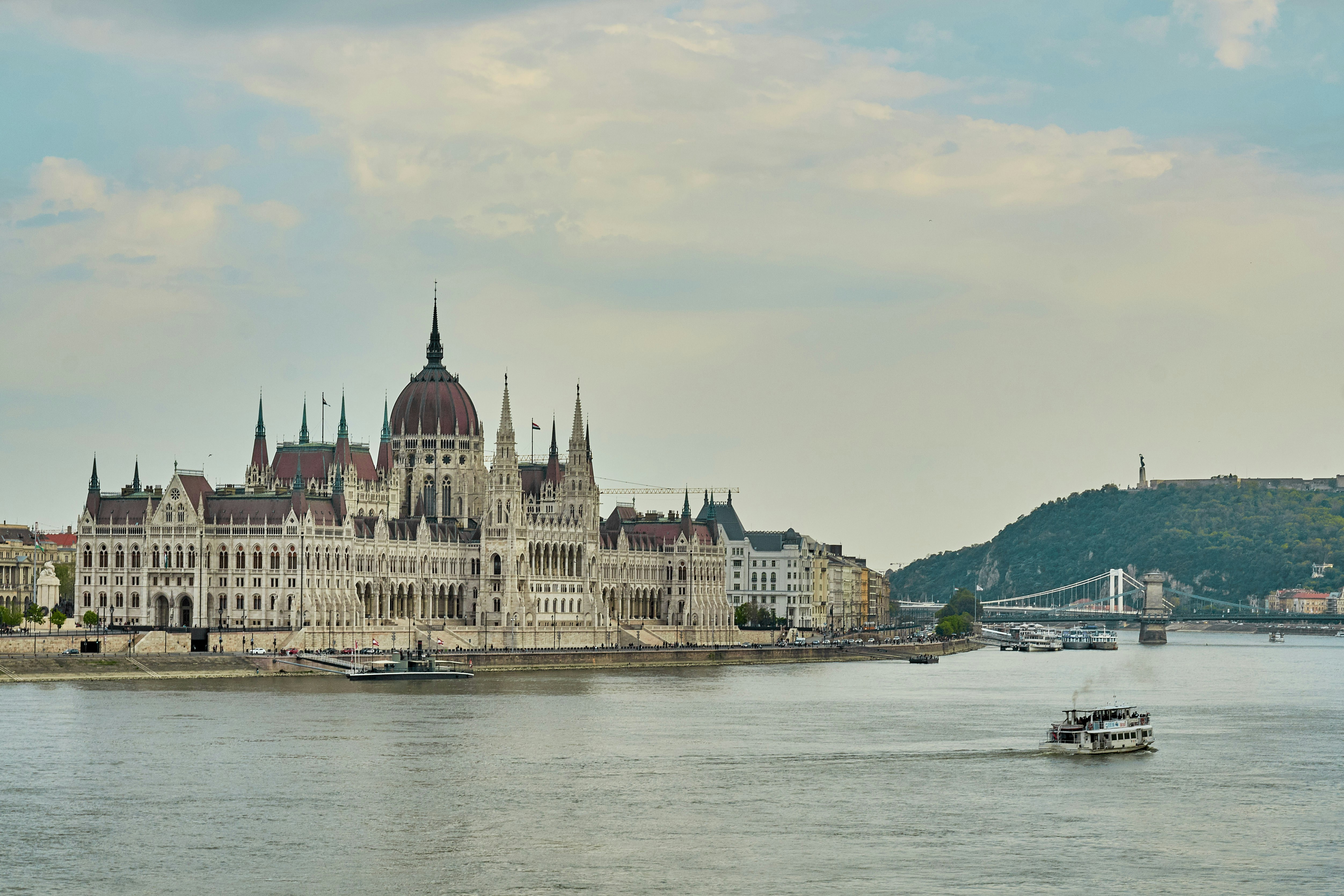 a large building with towers by a body of water with Hungarian Parliament Building in the background, 