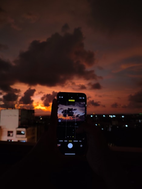 A cinematic black-and-white photo of a photographer capturing a dramatic sunset over a city skyline.