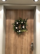 Decorative artificial flower wreath hanging on a wooden door.