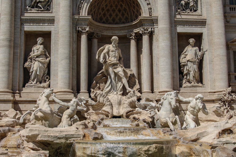 a fountain with statues in front of Trevi Fountain