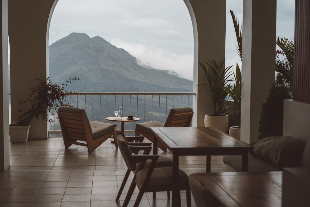 a patio with chairs and tables and a body of water in the background