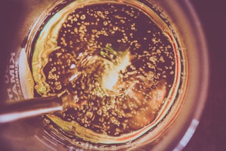 Close-up of a bubbling mead fermentation jar with golden hues and tiny air bubbles rising.