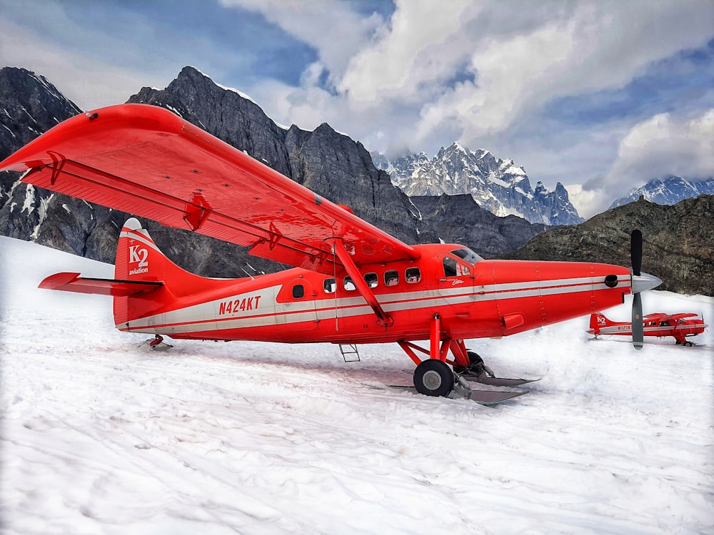 a red and white plane on a snowy mountain