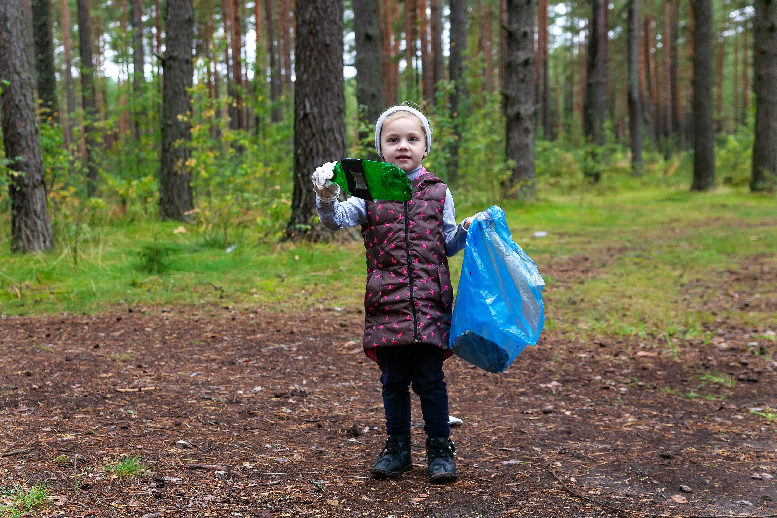 a child holding a book and a bag in a forest