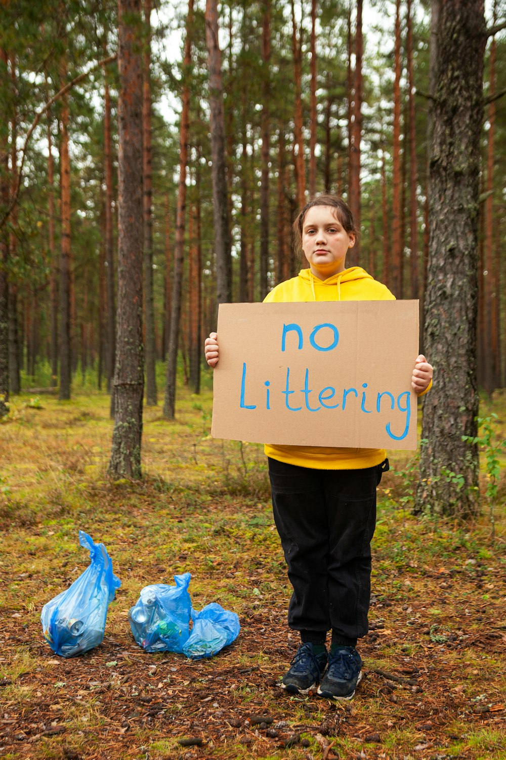 a boy holding a sign in the woods