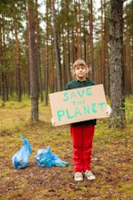 a boy holding a sign in the woods