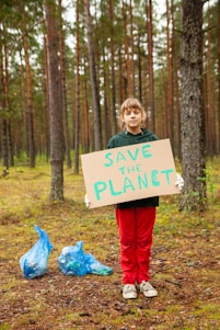 a boy holding a sign in the woods