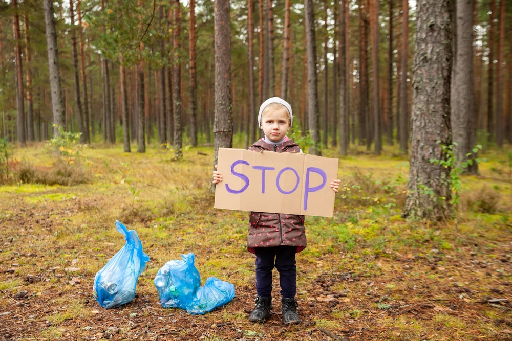 a child holding a sign in the woods