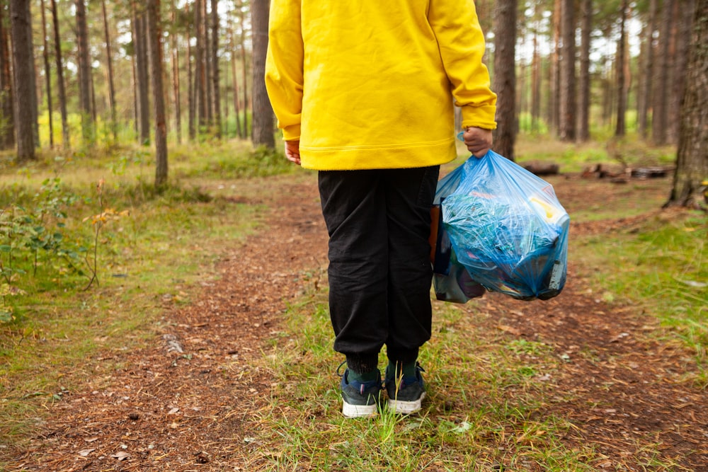 a person walking on a path with a bag of trash