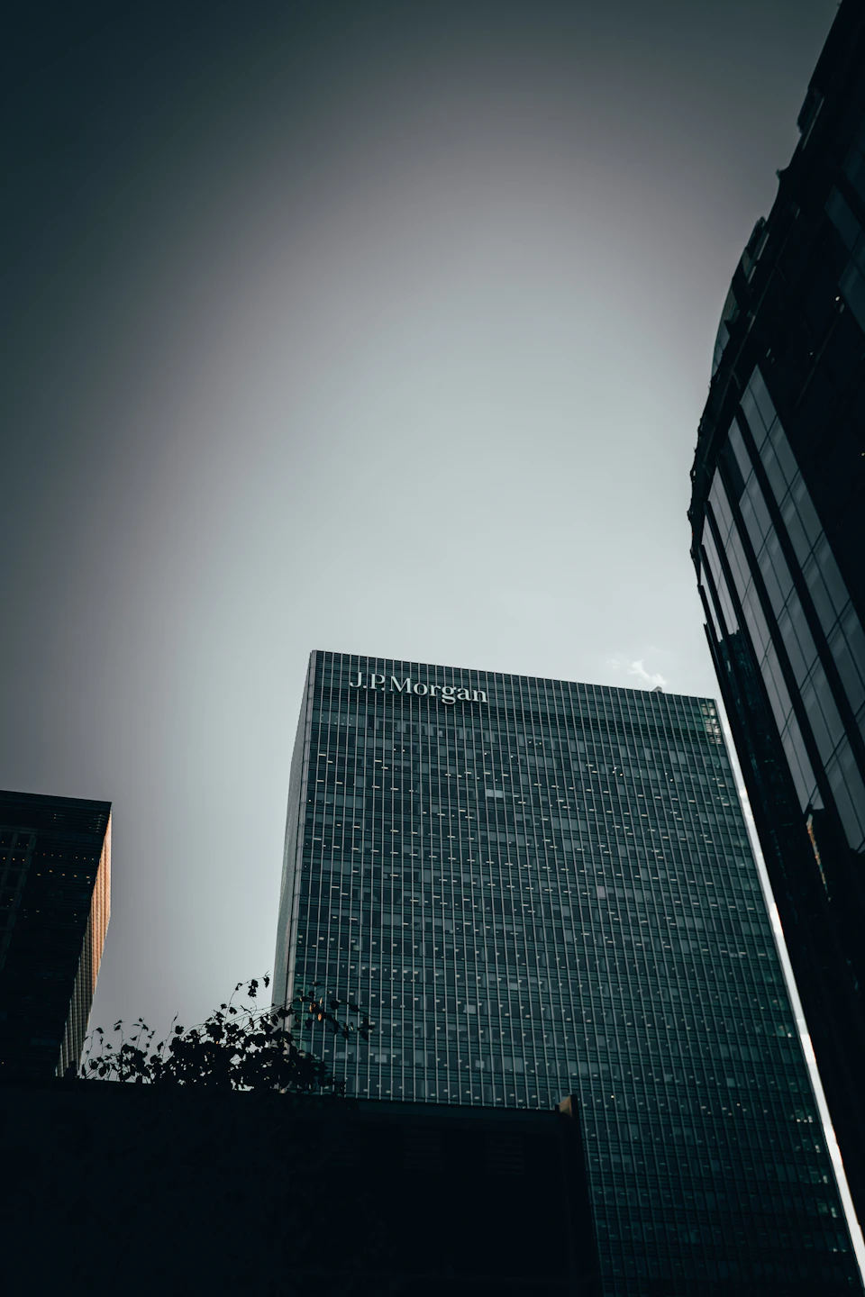 Three tall buildings with unique architectural styles and colors stand in cityscape