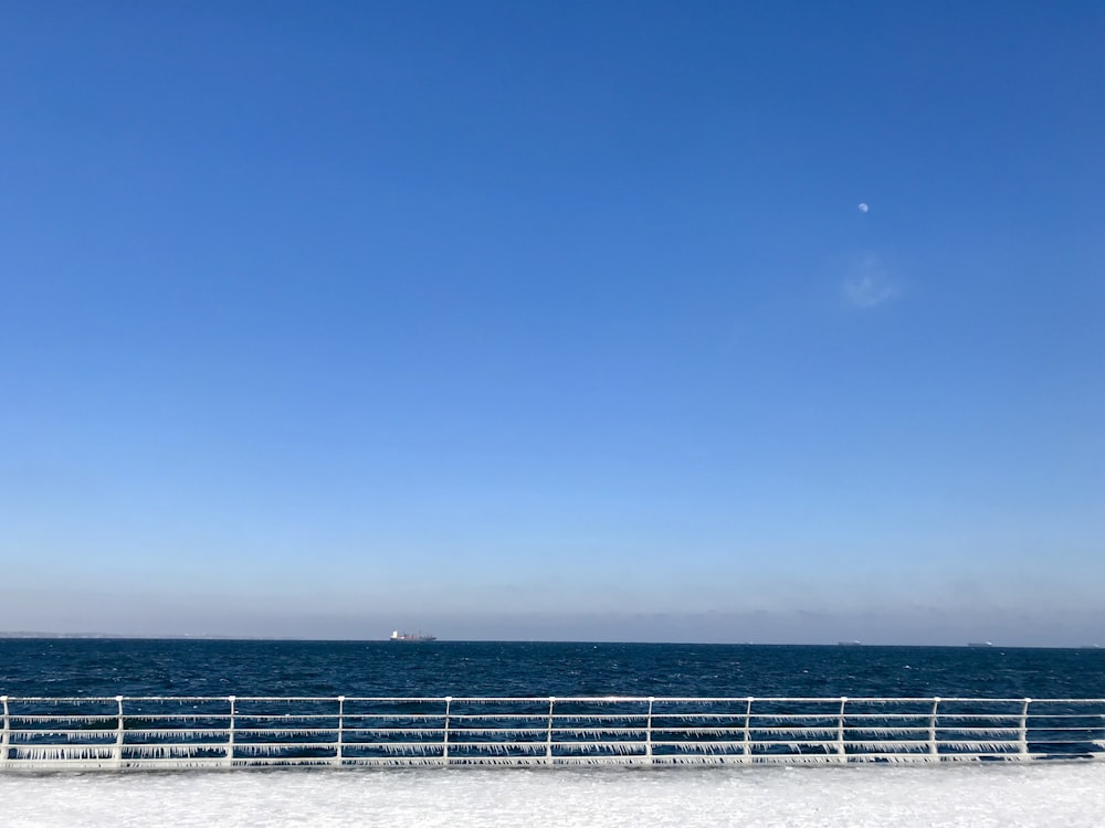 a beach with a railing and a body of water in the background