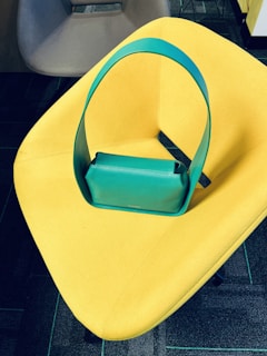 A vibrant turquoise wallet with a glossy finish and matching handbag peeking behind it