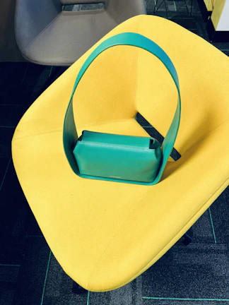 A stylish blue handbag hanging on a vintage chair in natural light.