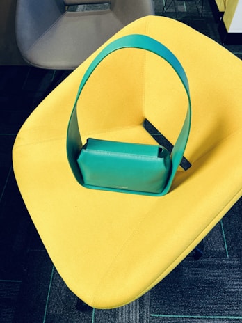 A vibrant accessory detail—a bold handbag resting on a sleek, modern chair.