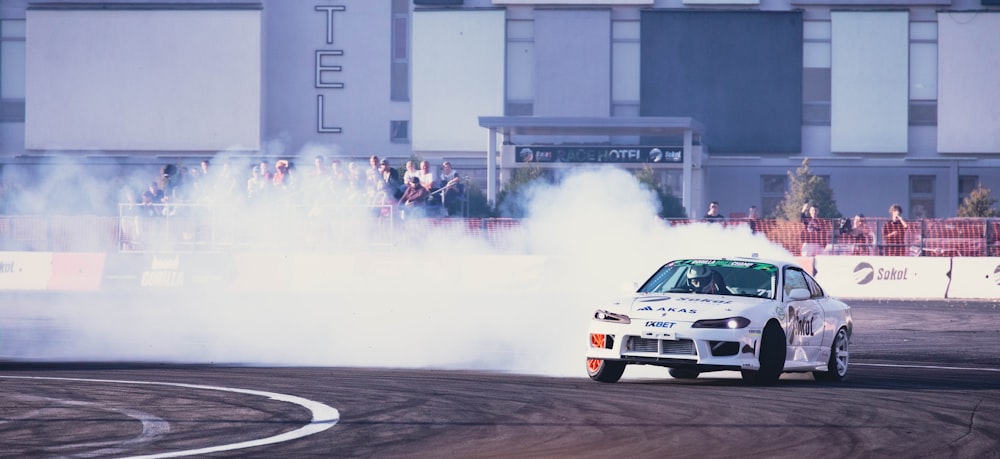 a white car driving on a road with a large explosion behind it