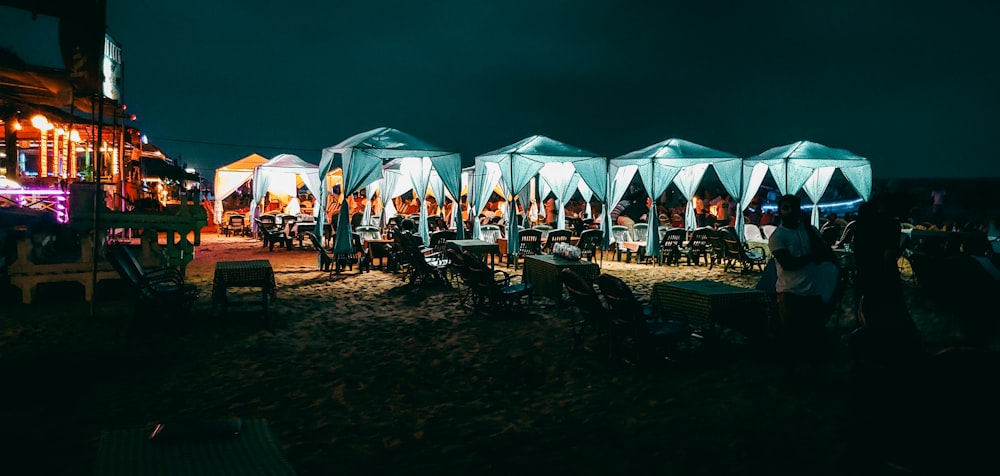a group of people sitting at tables under umbrellas at night