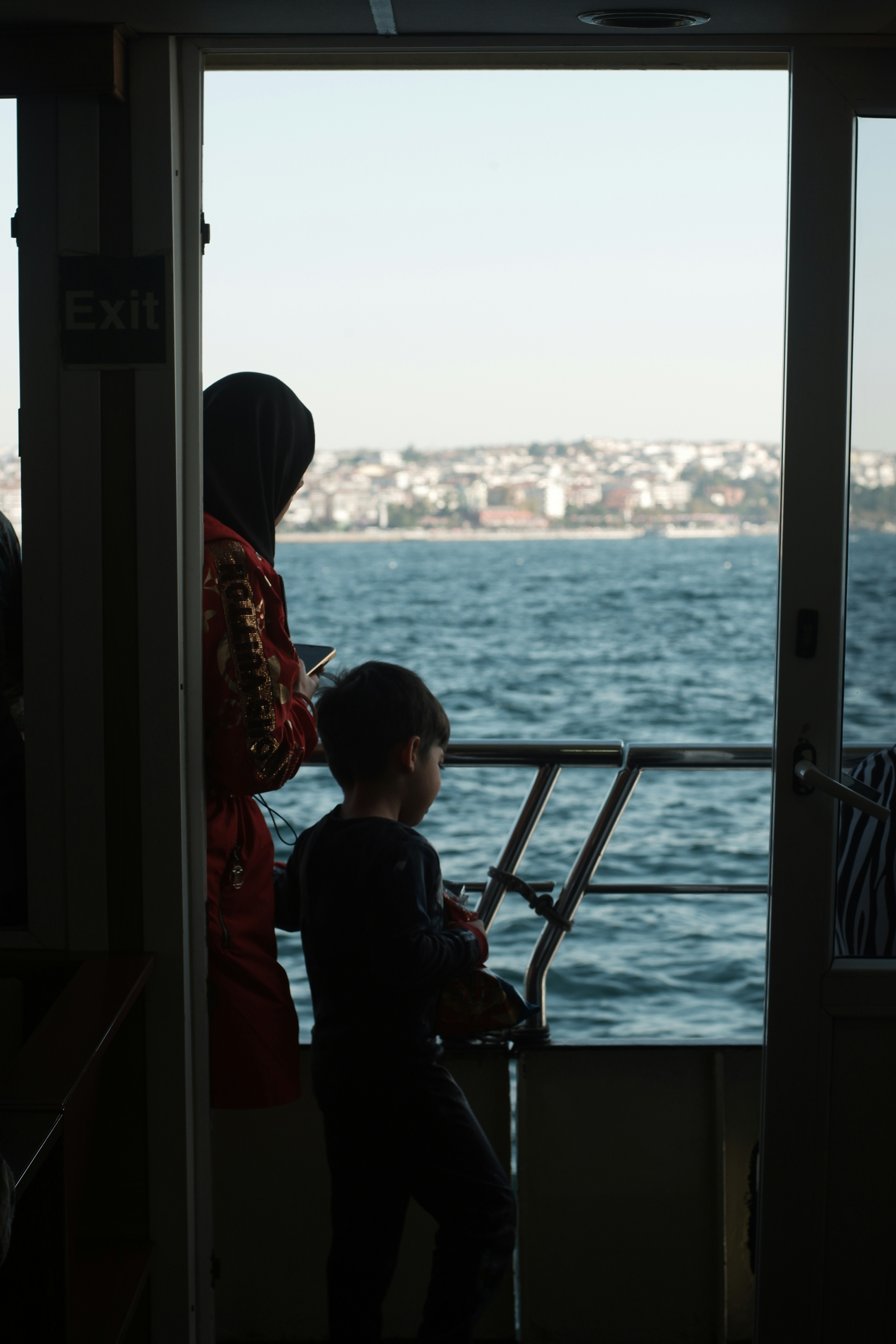 a man and a child looking out a window at the water
