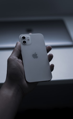 a hand holding a white cell phone