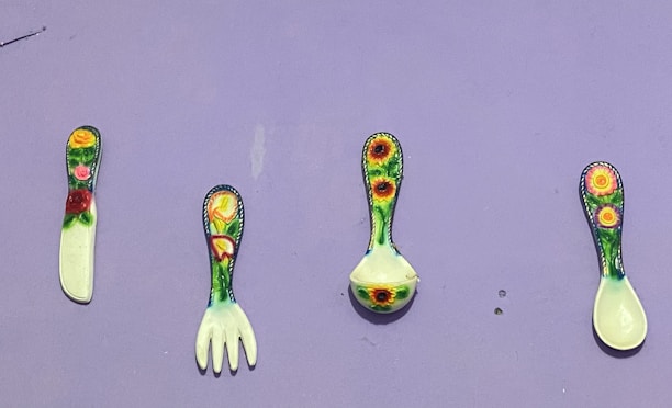 A variety of colorful kitchen utensils arranged on a wooden table.