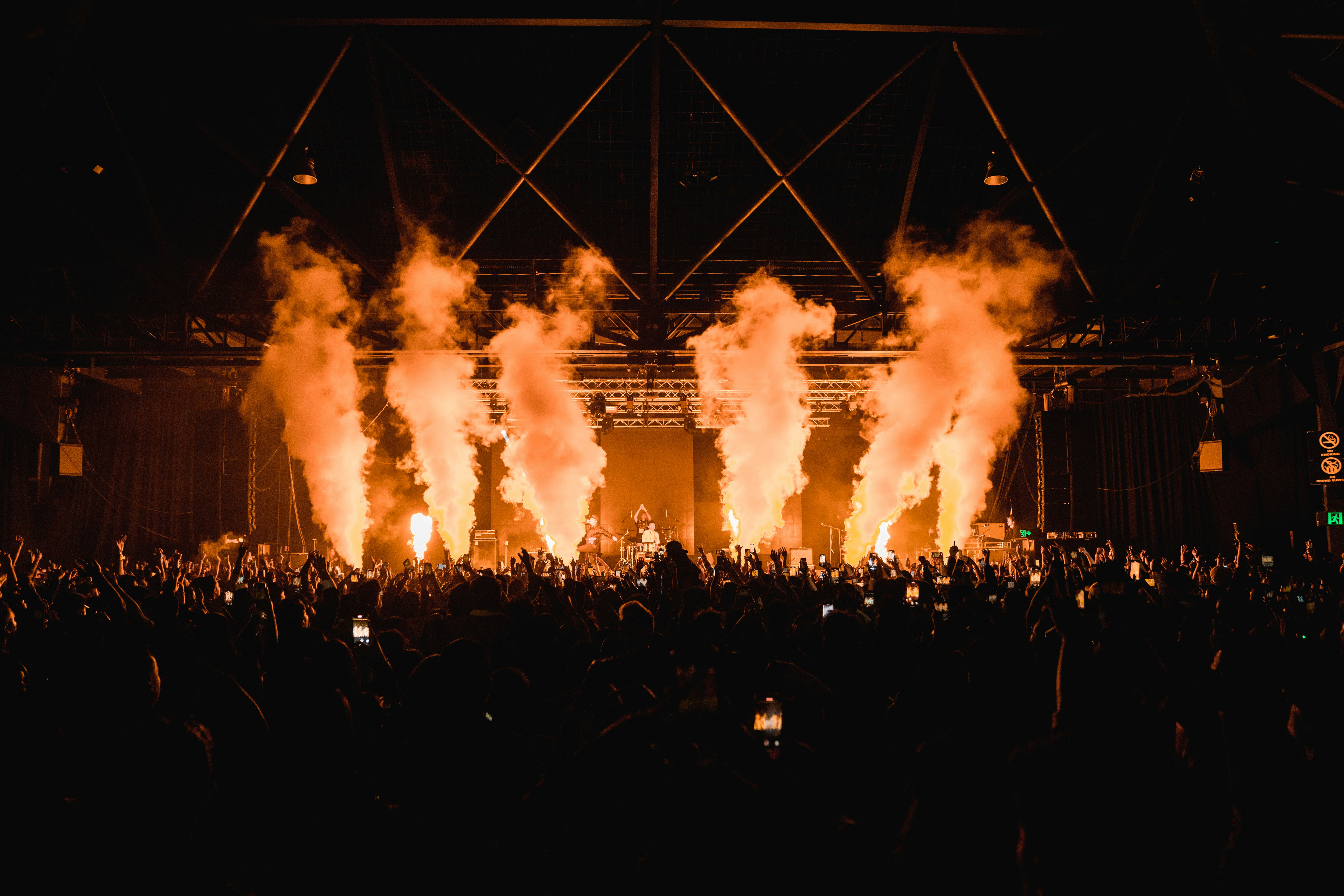 DJ performing at a console with a crowd in the background, with neon lights.