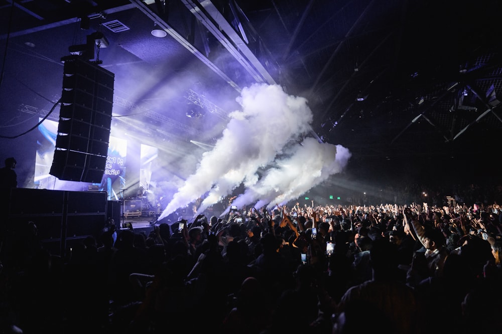 a large crowd of people in front of a stage with a large cloud of smoke