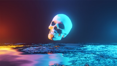 A glowing, floating skull with a neon blue hue dominates the dark background. The foreground features an abstract, reflective surface with a mix of blue, purple, and orange tones, giving a sense of an otherworldly or digital landscape.