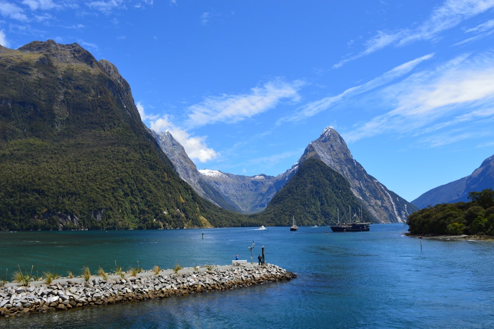 a body of water with boats and mountains in the background with Milford Sound in the background