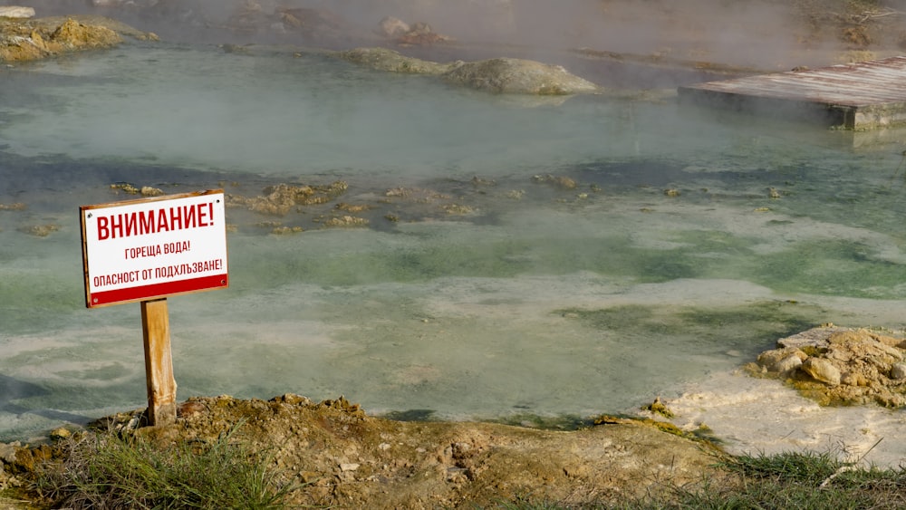 a sign in front of a body of water