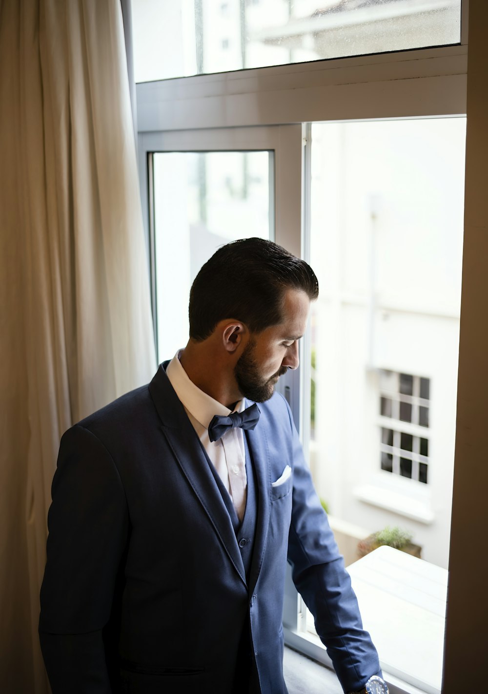 a man in a suit looking out a window