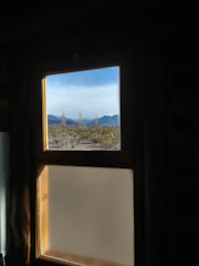 A clear glass window showing mountain views behind a desk with financial reports.