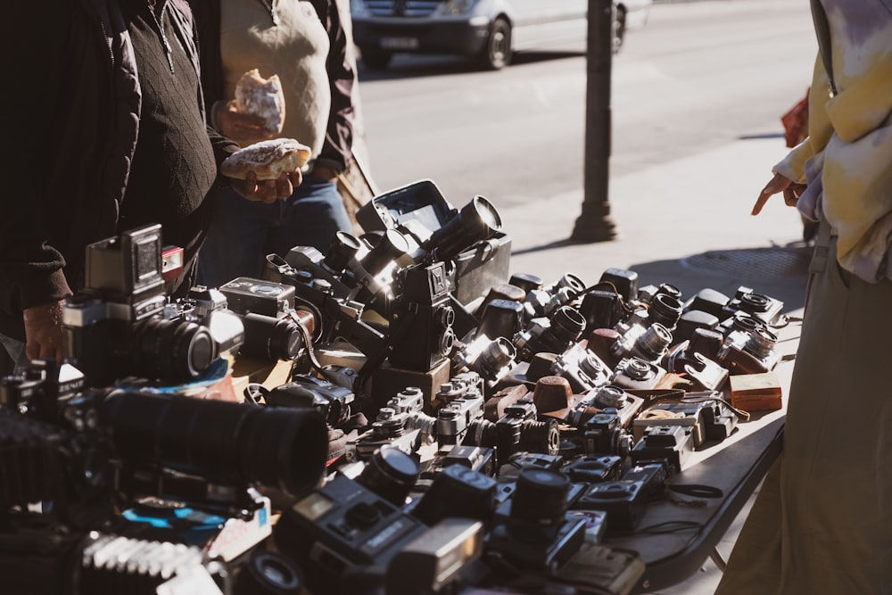 a group of people standing around a table full of cameras