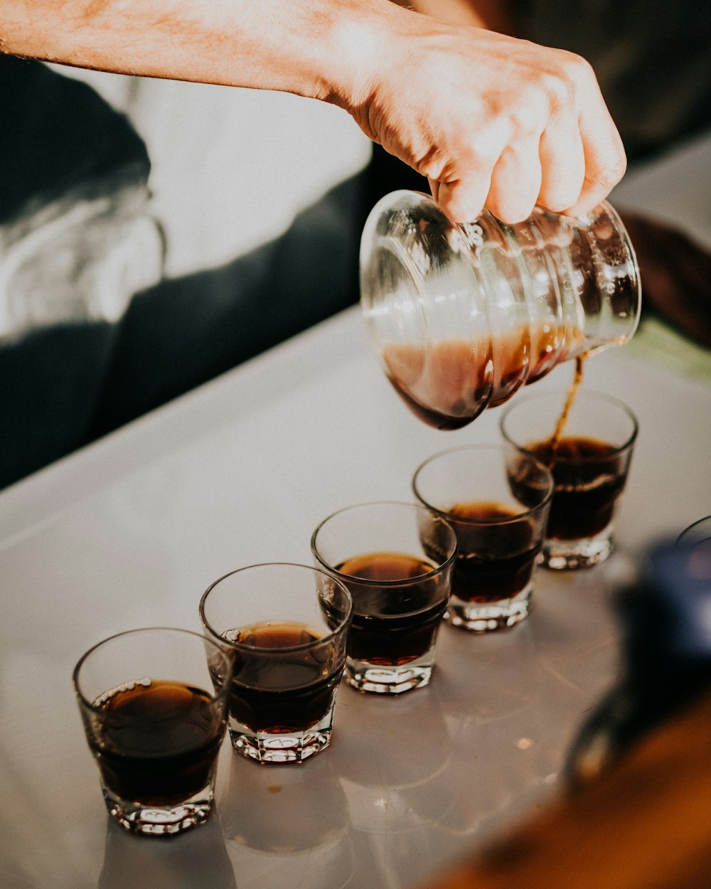 a hand pouring a drink into glasses