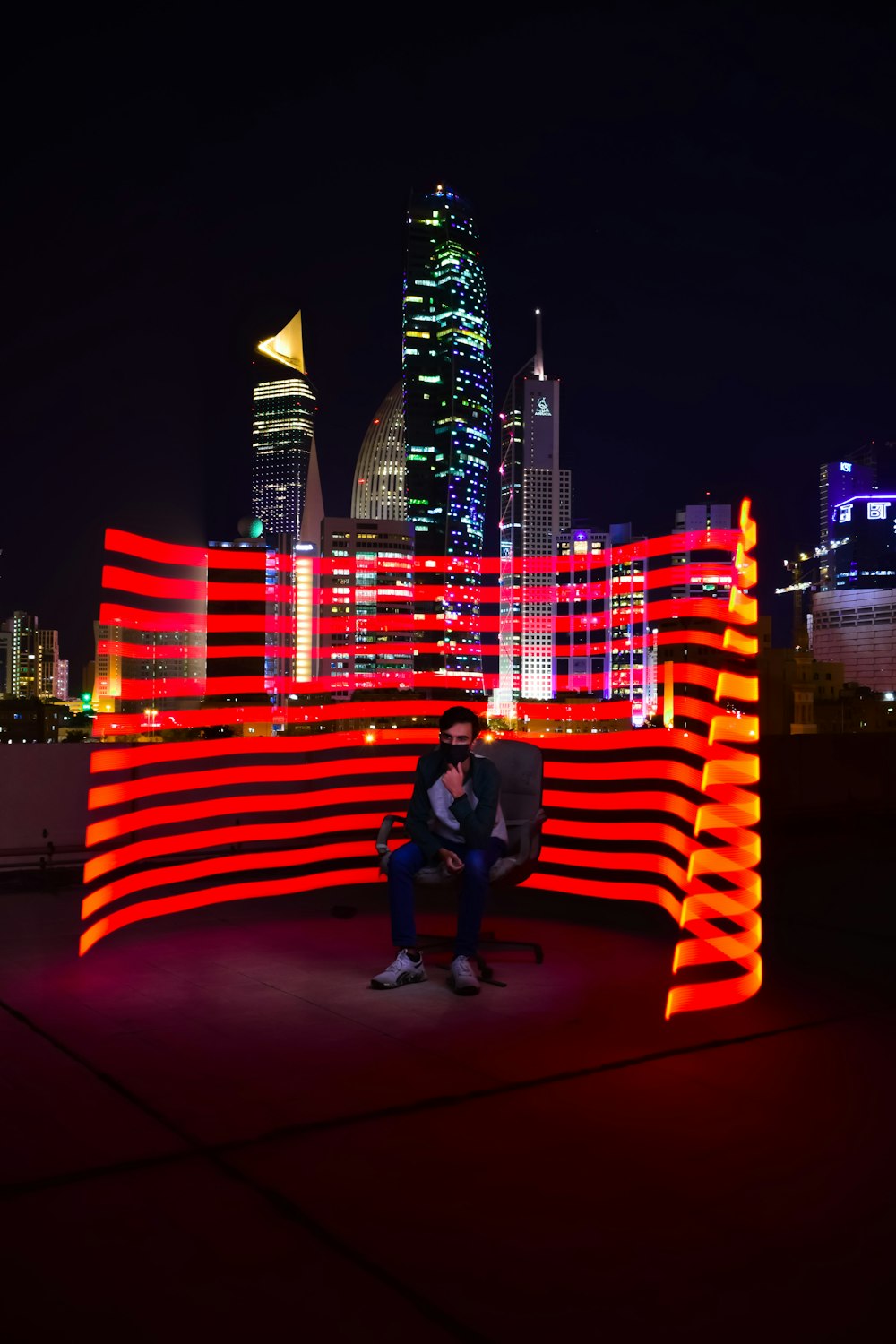 a person sitting on a bench in front of a city at night