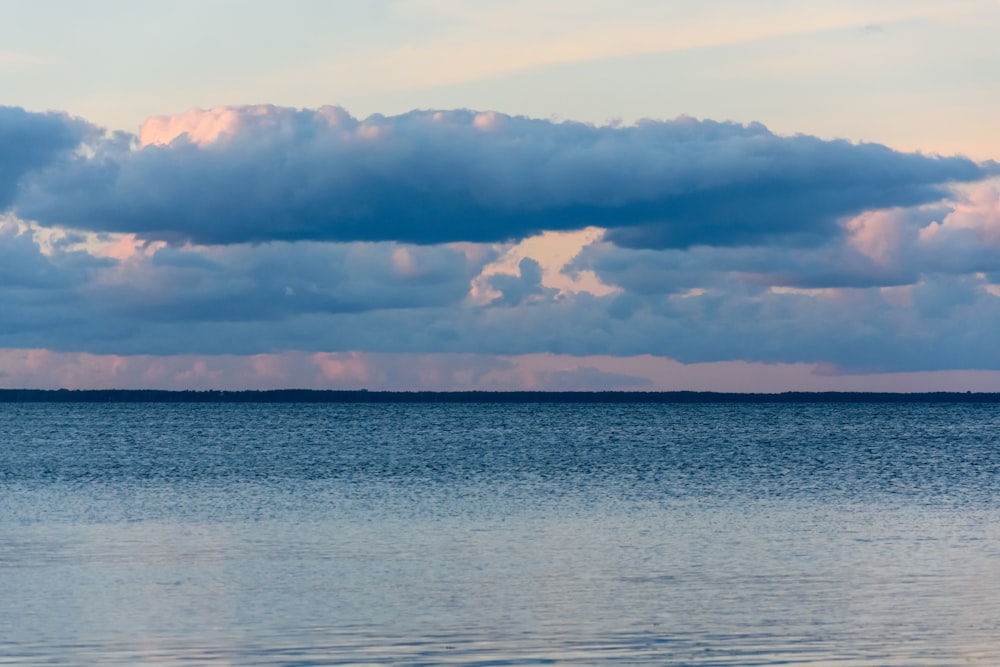 a body of water with clouds above it